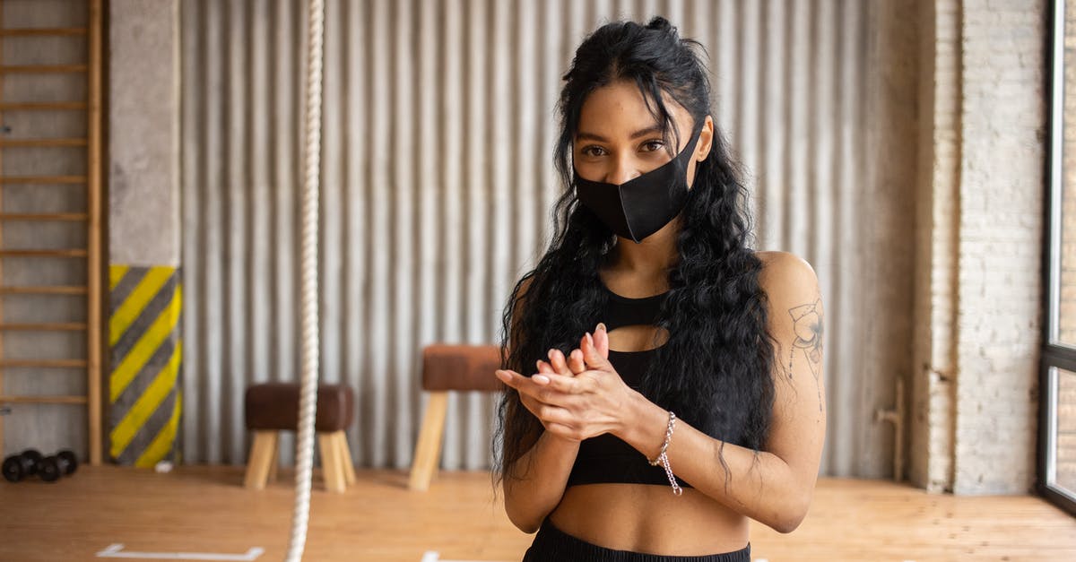 Why would I want to rub my friend's faces? - Young African American female in black protective mask rubbing hands and looking at camera in gym Why would I want to rub my friend's faces? - Young African American female in black protective mask rubbing hands and looking at camera in gym