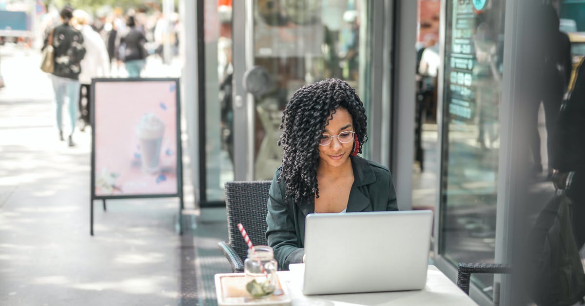 Why would I want to use Worldclay? - High angle of pensive African American female freelancer in glasses and casual clothes focusing on screen and interacting with netbook while sitting at table with glass of yummy drink on cafe terrace in sunny day