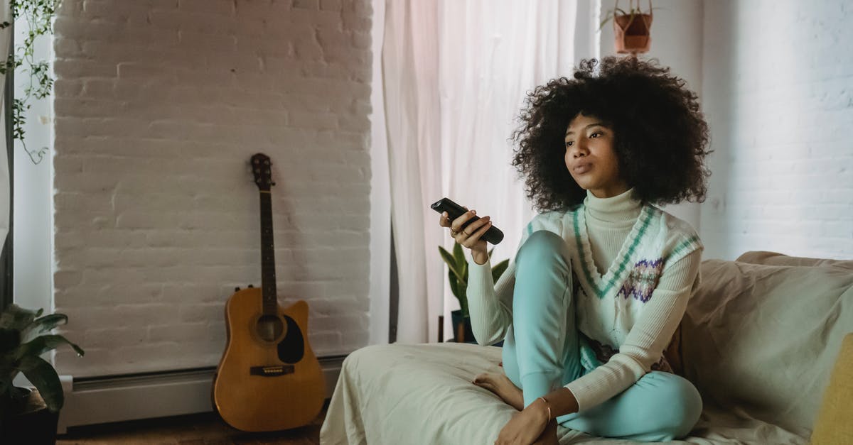 Wii remotes disconnect as soon as I enter a channel - Young black lady resting on sofa and watching TV at home Wii remotes disconnect as soon as I enter a channel - Young black lady resting on sofa and watching TV at home