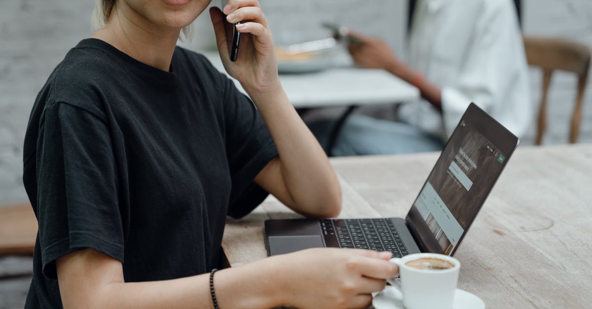 Wii remotes won't sync to Wii - Crop Asian lady in black tee making phone call while sitting at table with coffee and laptop in cafe Wii remotes won't sync to Wii - Crop Asian lady in black tee making phone call while sitting at table with coffee and laptop in cafe