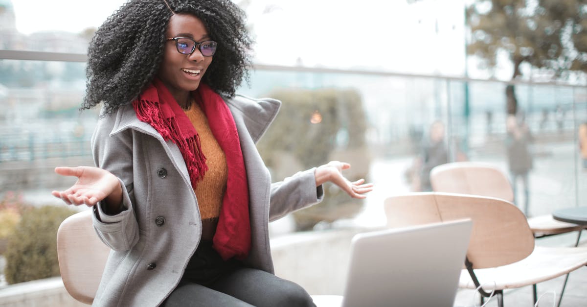 Wii U has no Video Output - Happy excited African American female laughing and gesticulating while having video calling on laptop and sitting at modern cafe