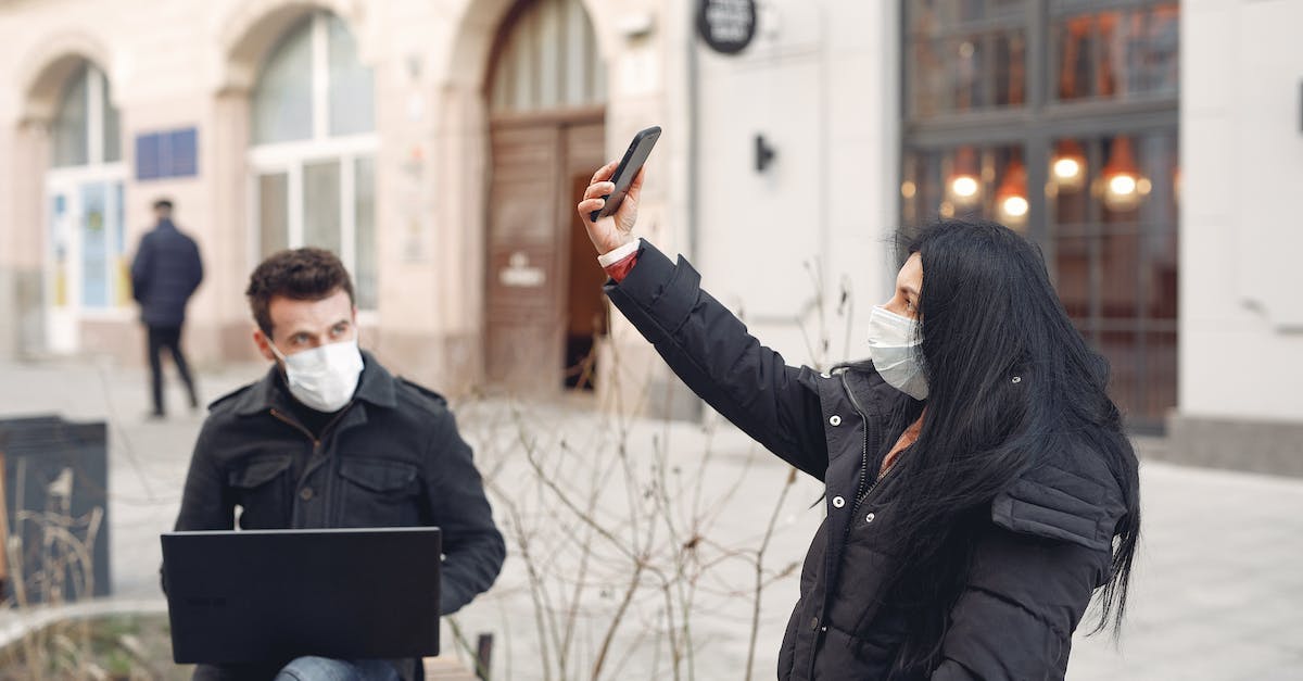 Will a shop which takes health take armoured hearts first? - Young couple wearing medical masks using laptop and smartphone on city street