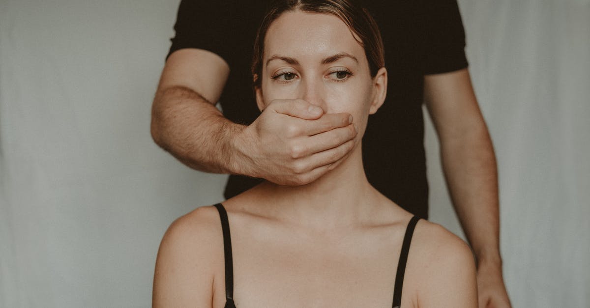 Will I have problems because of a harassment warning? - Unrecognizable male covering mouth of frighted vulnerable female with hand while standing behind back on white background in light room Will I have problems because of a harassment warning? - Unrecognizable male covering mouth of frighted vulnerable female with hand while standing behind back on white background in light room