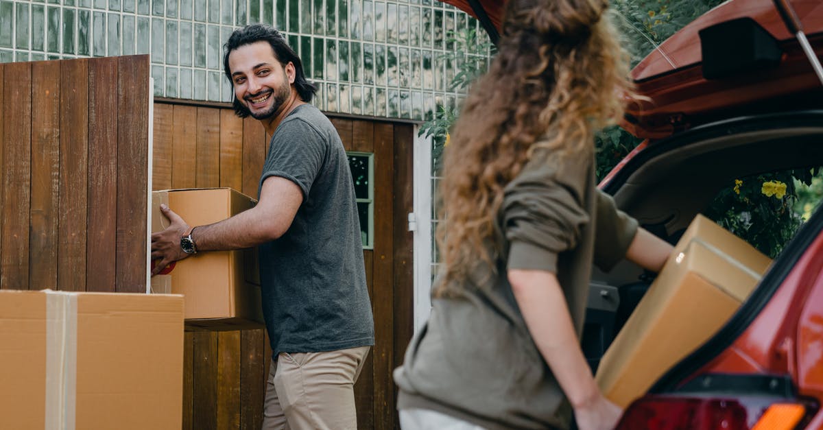 Will I have to buy a new clan? - Cheerful modern male and female in comfortable casual clothes unpacking car trunk in green garden of new house while moving in together