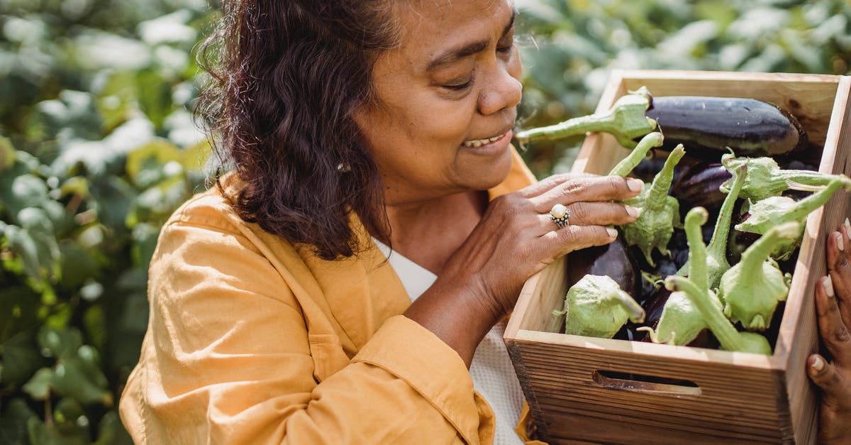 Will plants continue to produce crops in their second season if not removed? - Crop happy middle aged ethnic female farmer in casual clothes standing in garden with box of fresh ripe eggplants after harvesting on sunny day