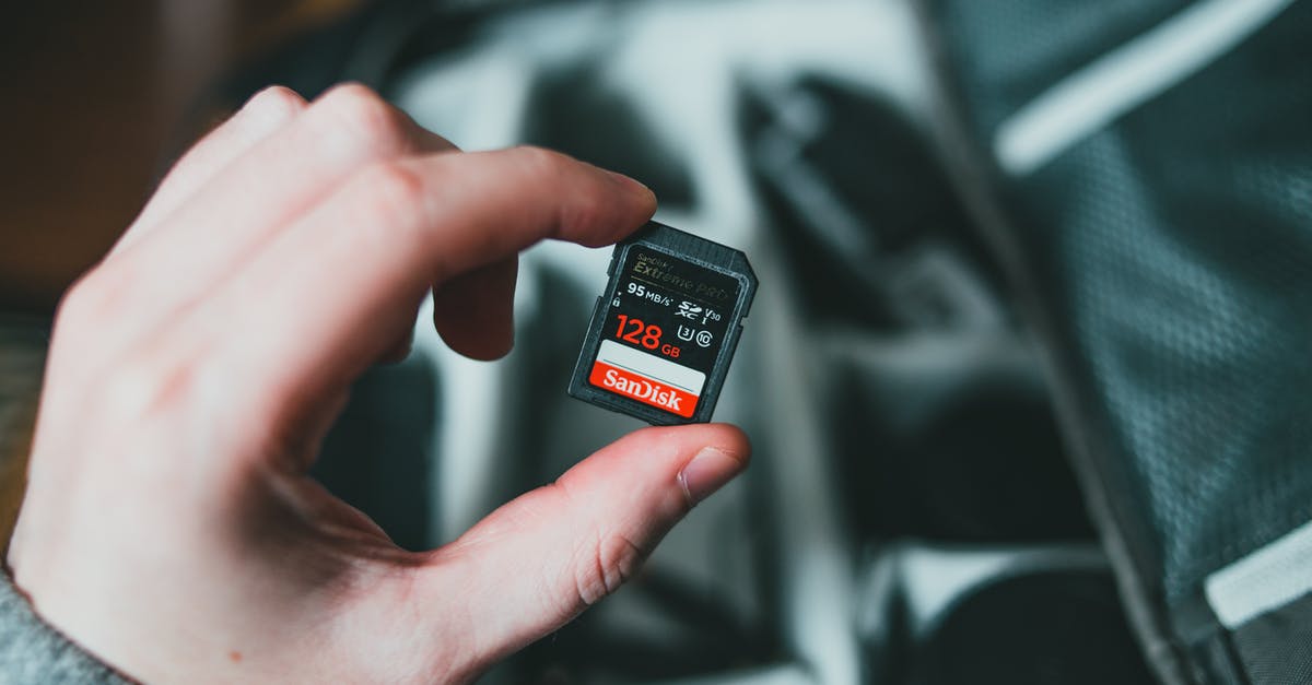 Will putting a camera SD card into my 3DS remove existing data? - From above of crop anonymous male holding modern portable 128 gb memory card above bag with equipments