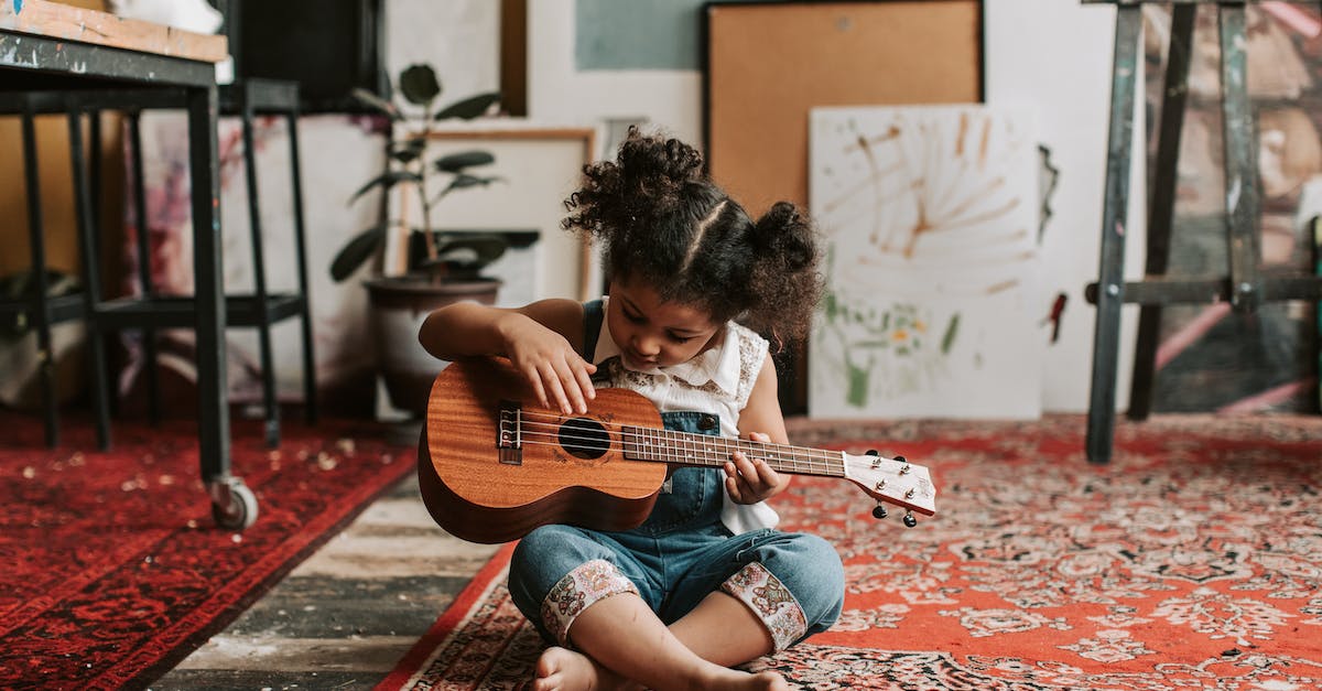 Will steam workshop download mods while playing a game? - A Young Girl in Denim Jumper Sitting on the Floor while Playing Ukulele