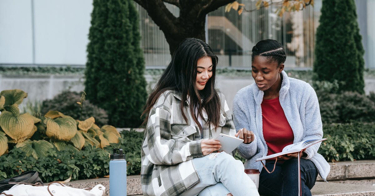 Will the journal show when I overtake gyms? - Smiling multiethnic girlfriends talking and sharing smartphone on street bench Will the journal show when I overtake gyms? - Smiling multiethnic girlfriends talking and sharing smartphone on street bench