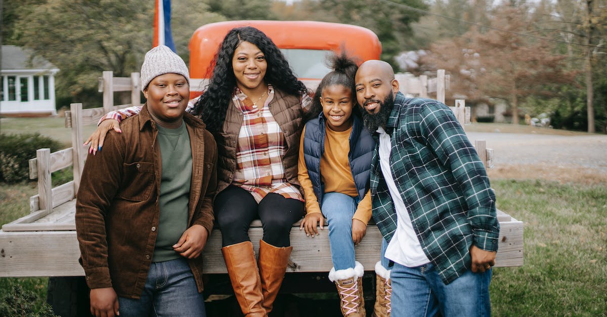 Will wearing special outfits during smile time affect a child? - Cheerful African American family embracing near vehicle on farm