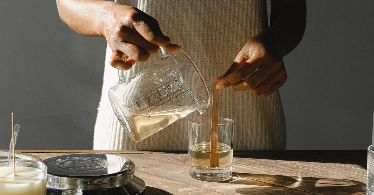 Witcher 3 - Melt Armor skill - Unrecognizable African American female pouring melted wax from beaker into glass mold with wooden wick while making candles at table