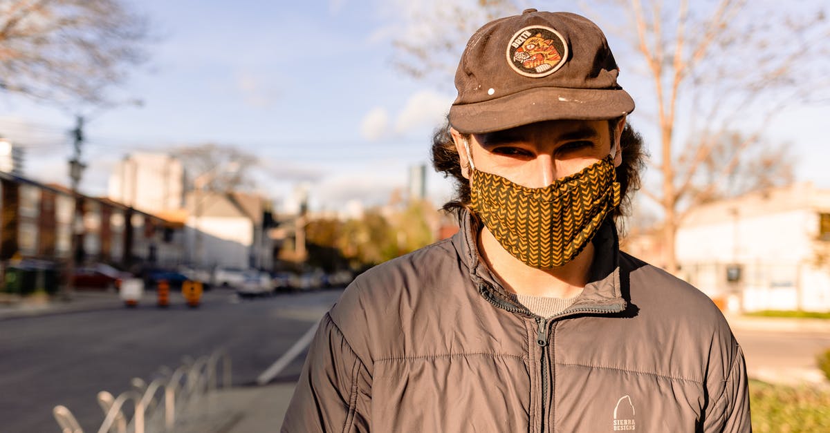Witcher 3 New Game+ Level Cap - Anonymous male in fabric mask and cap looking at camera while standing on street pavement in autumn in sunlight during quarantine period Witcher 3 New Game+ Level Cap - Anonymous male in fabric mask and cap looking at camera while standing on street pavement in autumn in sunlight during quarantine period