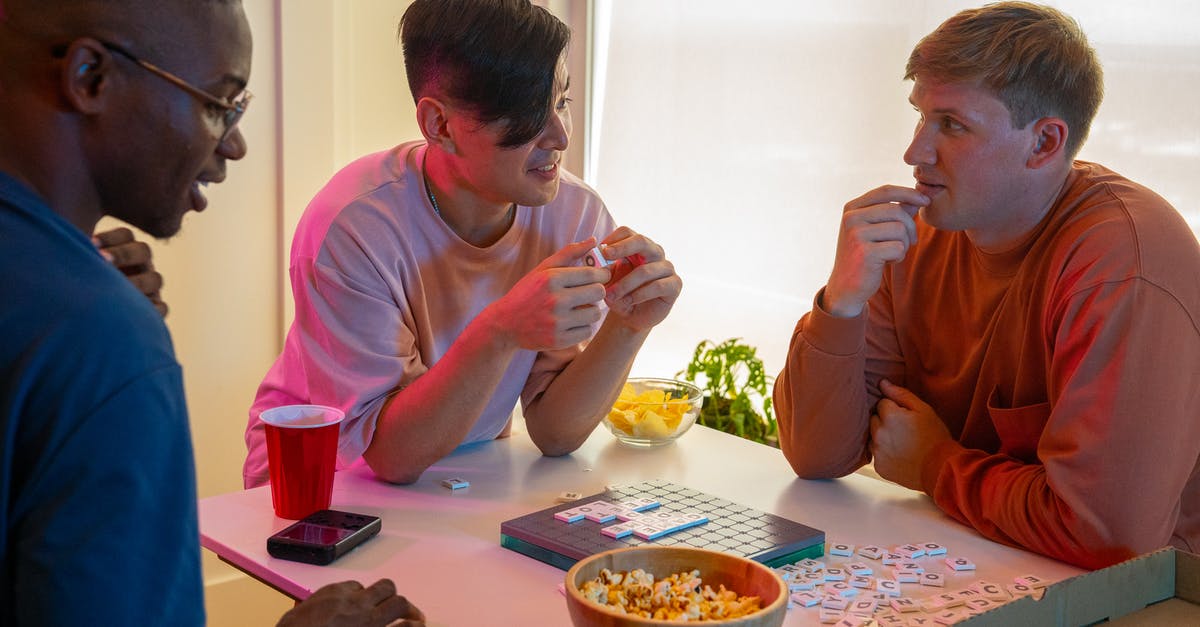 Words with friends - playing with “ the Masters” - Man in Pink Crew Neck T-shirt Sitting Beside Woman in Orange Long Sleeve Shirt Eating