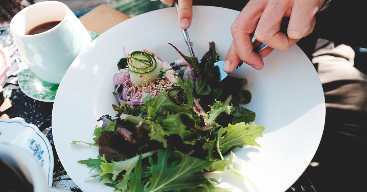 WoW upgrading from starter edition - High angle crop anonymous male with cutlery eating tasty mix leaves salads in outdoor restaurant on sunny weather