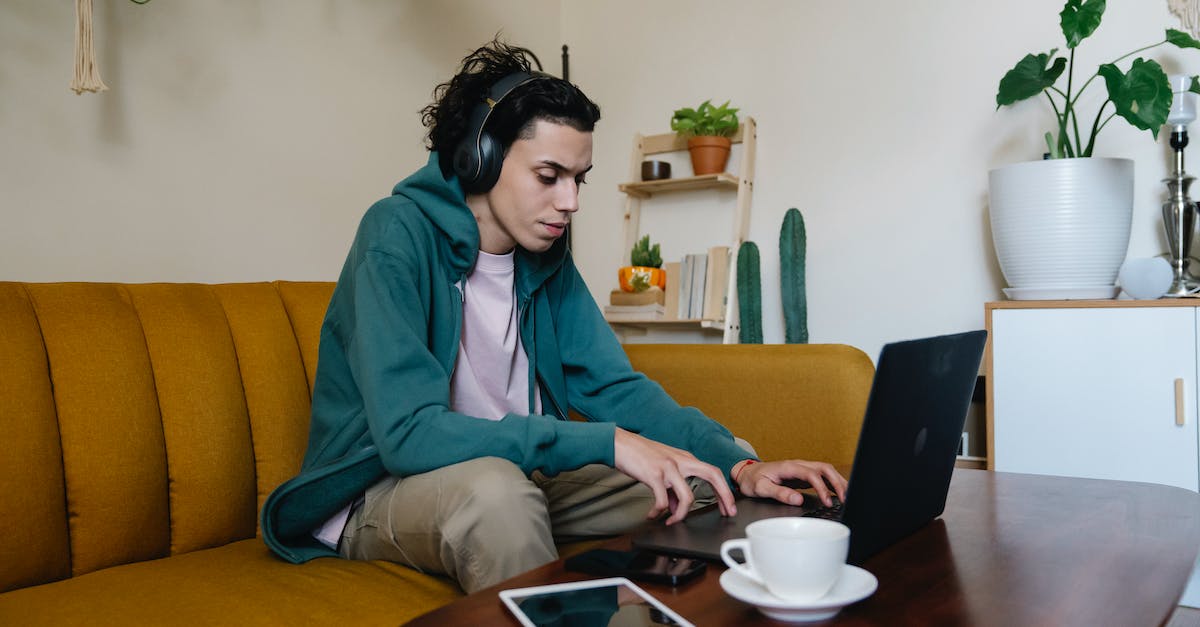 Xbox 360 freezes at startup screen, audio still works, input does not - Attentive ethnic male remote worker in headset browsing internet on netbook while sitting at desk with tablet and hot drink in house